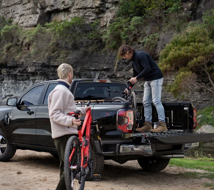 Two people putting bikes into the trunk.