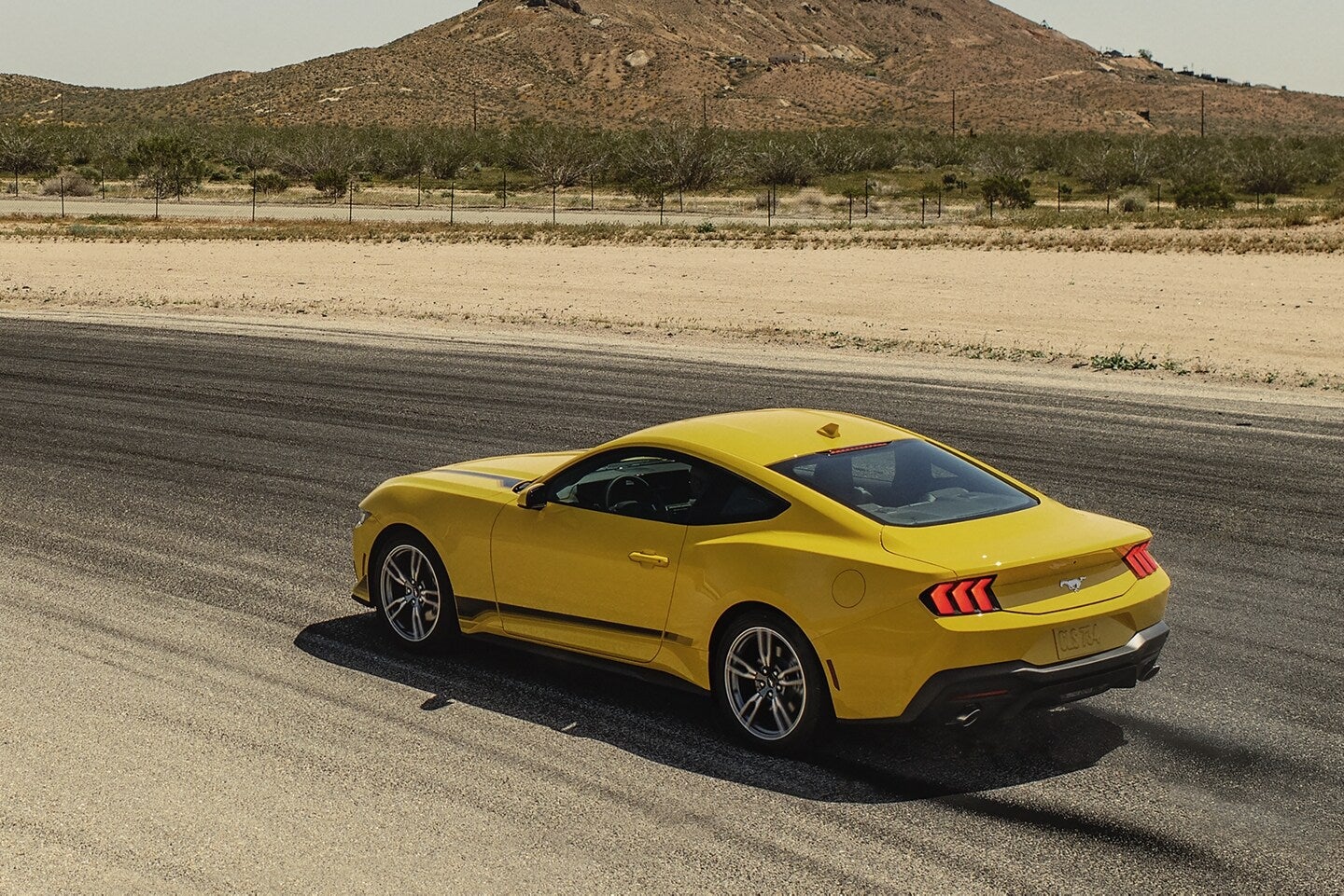 a yellow 2024 ford mustang car on the road