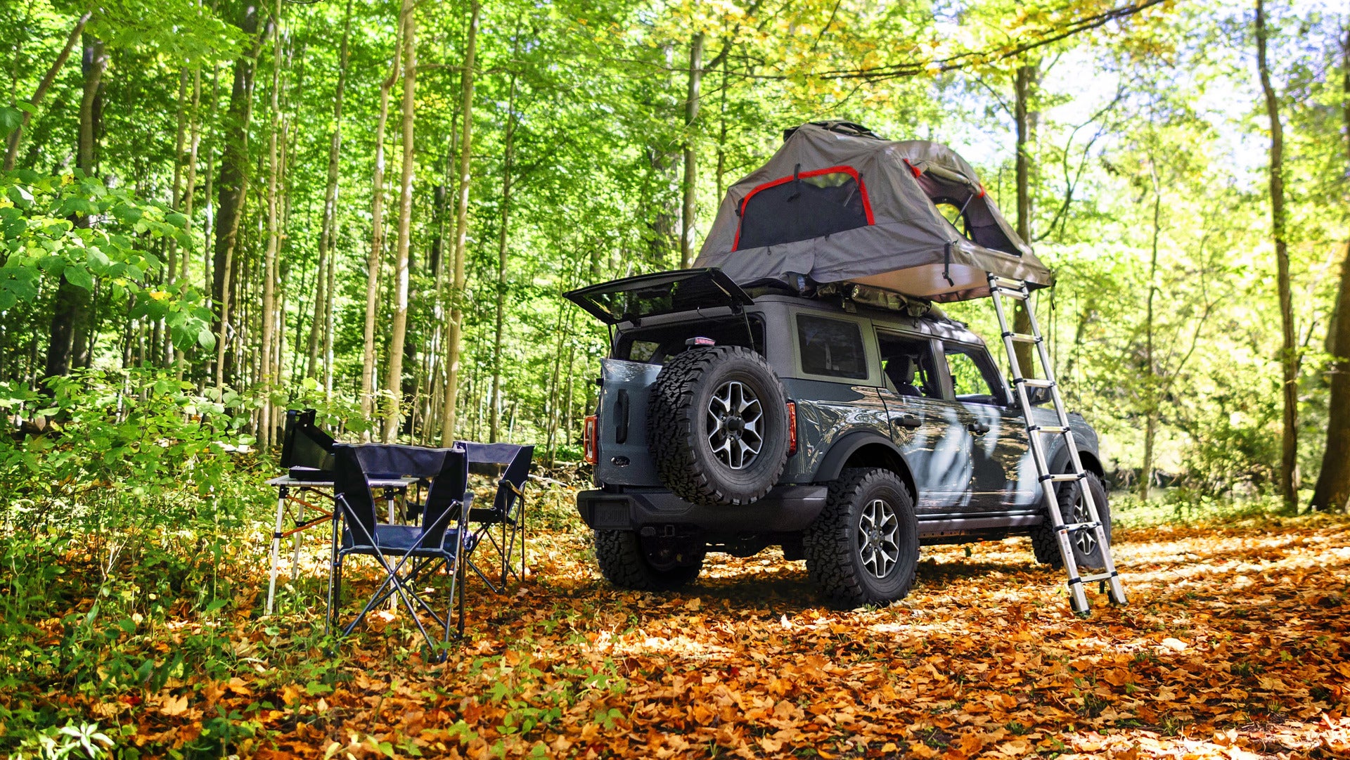 A green bronco with a tent on the top.
