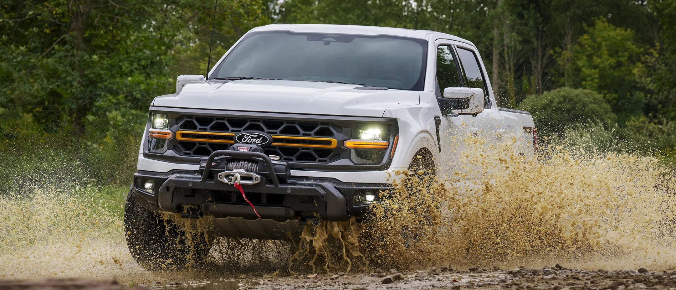 a white ford f-150 tremor in white driving in muddy water