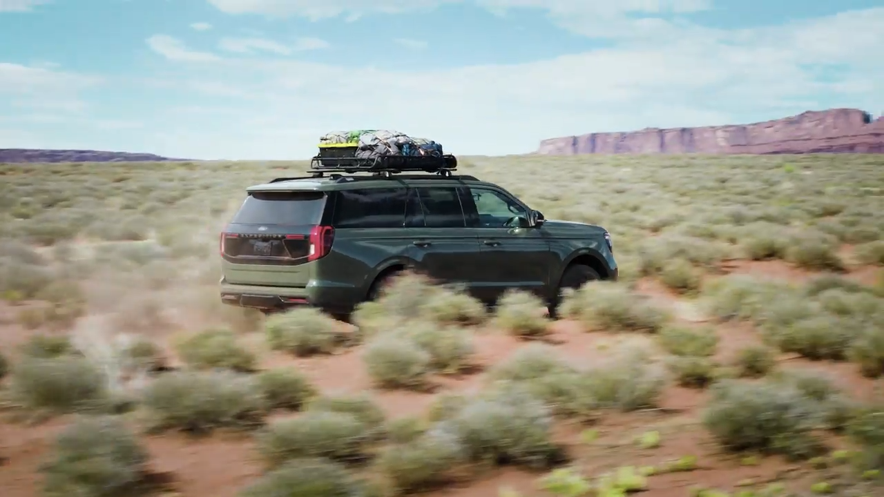 Ford Expedition driving over a bridge at sunset, showcasing its powerful presence and LED headlights.
