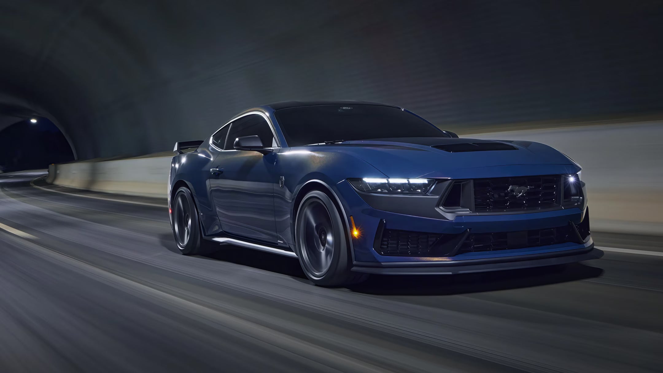 Front view of a convertible 2025 Ford Mustang in cream color against a bold red background.