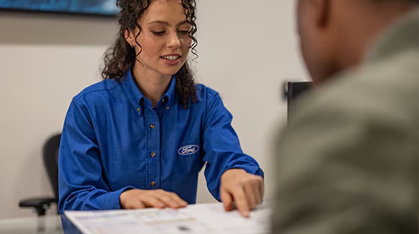 a view of a ford service women helping a customer with the maintenance schedule for a 2026 Ford Explorer
