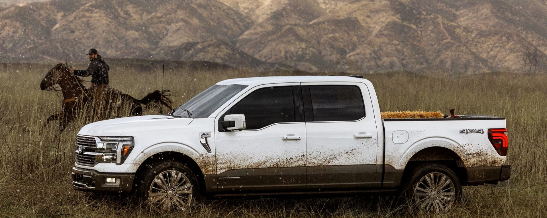 A white ford f-150 driving through the mud.