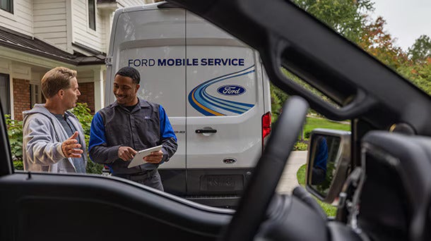 two men talking next to a Ford Vehicle