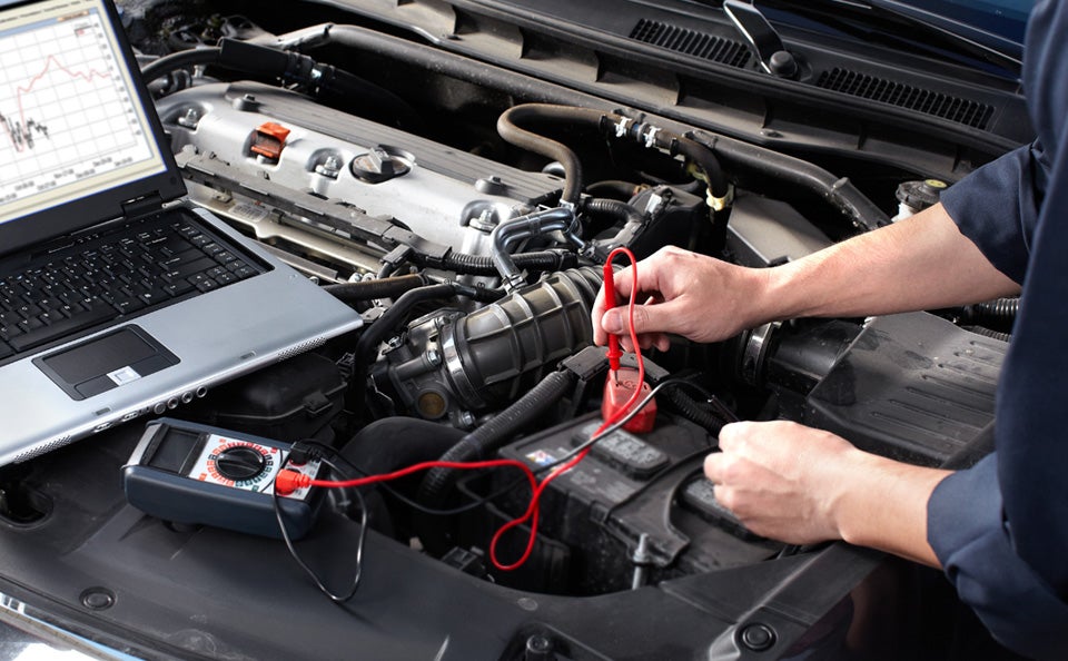 A man looking at the battery in a car.